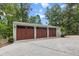 Spacious three-car garage with stained wood doors, surrounded by beautiful landscaping and mature trees at 206 Chaussee Blvd, Summerville, SC 29483