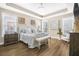 Spacious main bedroom with tray ceilings, wood floors, bench, and elegant decor at 218 River Martin Ct, Summerville, SC 29483