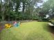 Spacious backyard with grass, trees, landscaping, and colorful Adirondack chairs at 2204 Andover Way, Mount Pleasant, SC 29466