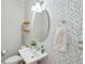 Stylish powder room featuring a pedestal sink, oval mirror, decorative wallpaper, and open shelving at 262 Great Lawn Dr, Summerville, SC 29486