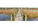 Scenic boardwalk extending through a serene marsh, connecting to elegant waterfront homes in the distance at 2705 Parkers Landing Rd, Mount Pleasant, SC 29466