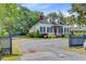 Beautifully landscaped home with a red door, green shutters, and a spacious gravel driveway at 318 N Magnolia St, Summerville, SC 29483