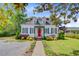 Quaint home featuring a red door, dormer windows, black shutters, and a well-maintained front yard at 318 N Magnolia St, Summerville, SC 29483