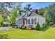 Charming white home with a red door, green shutters, dormer windows, and manicured landscaping at 318 N Magnolia St, Summerville, SC 29483
