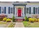 Inviting front porch with a red door, black shutters, and lush landscaping at 318 N Magnolia St, Summerville, SC 29483