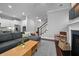 Open-concept living room featuring a gray sectional, modern coffee table, and access to staircase at 410 Eliston St, Summerville, SC 29486