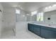 Bright bathroom featuring marble floors and shower, and double sink vanity with custom blue cabinets at 5525 Alpine Dr, Summerville, SC 29483