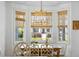 Bright and sunny dining area features a wooden table, bamboo blinds, and an elegant chandelier at 601 King Haven Ln, Johns Island, SC 29455