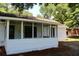 Side view of a quaint house with a screened porch and natural landscaping at 7774 Ginger Ln, North Charleston, SC 29420