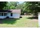 Side view of a white house with a screened porch, green lawn, and a gated yard beyond at 7774 Ginger Ln, North Charleston, SC 29420