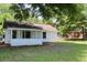 Side view of a quaint house with a screened porch and natural landscaping at 7774 Ginger Ln, North Charleston, SC 29420