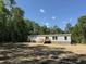 Side angle of a manufactured home with grey siding, brick skirting, a small porch and wood deck in the rear at 852 Lawyer Ln, Cross, SC 29436