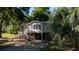 Exterior view of the raised home featuring a stairway, a screened porch and a spacious yard at 1195 Framptons Inlet Rd, Edisto Island, SC 29438