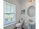 Well-lit half bathroom with a pedestal sink, round mirror, and a view from the window at 175 Darby Meadow Ln, Ridgeville, SC 29472
