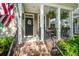 Charming front porch with decorative planters, ferns, American flag, and black front door at 1852 Pierce St, Charleston, SC 29492