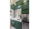 Stylish kitchenette with emerald cabinets, stainless steel refrigerator, gold hardware, and geometric wallpaper at 19 Smith St # A, Charleston, SC 29401