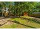 Spacious backyard with a charming shed surrounded by lush greenery and mature trees at 2468 Marina Rd, Wadmalaw Island, SC 29487