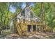 Picturesque coastal home with elevated deck, surrounded by lush trees and beautiful landscaping at 2468 Marina Rd, Wadmalaw Island, SC 29487