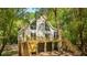 Charming elevated beach house featuring large windows and a spacious deck surrounded by trees at 2468 Marina Rd, Wadmalaw Island, SC 29487