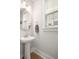 Bright powder room featuring a pedestal sink, round mirror, and neutral color scheme at 2747 Calico Bass Ln, Johns Island, SC 29455