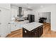 A modern white kitchen features stainless steel appliances, marble countertops, and a stylish dark wood island at 277 Fiddleback Dr, Summerville, SC 29486