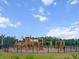 Large wooden community playground surrounded by a secure fence, set against a backdrop of trees at 277 Fiddleback Dr, Summerville, SC 29486