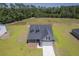 A gray home with a black roof and a concrete driveway nestled in an area with a field and woods at 306 Mizell Rd, Dorchester, SC 29437