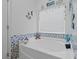 Bright bathroom with a white tub, blue accent tiles, and beach-themed window decor at 346 Cicadas Song, Moncks Corner, SC 29461
