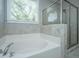 Bright bathroom featuring a soaking tub and a glass-enclosed shower with tiled walls and a window at 3711 Tip Ln, Mount Pleasant, SC 29466