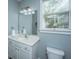 This well-lit bathroom features a white sink and vanity with a mirror and a view outside the window at 3711 Tip Ln, Mount Pleasant, SC 29466