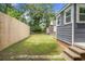 A grassy backyard featuring a wooden fence, partial view of the gray house, and mature trees at 3935 Walnut St, North Charleston, SC 29405