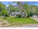 Inviting single-story home with a well-maintained lawn, mature trees, and solar panels installed on the roof at 4 Garth Dr, Charleston, SC 29414