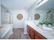 Well-lit bathroom with double vanity, soaking tub, shower, and wood-look floors offers a spa-like experience at 414 Dovetail Cir, Summerville, SC 29483