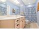 Well-lit bathroom featuring a cream vanity, stylish blue wallpaper, and coordinated shower curtain at 5032 Coral Reef Dr, Johns Island, SC 29455