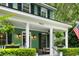 Inviting porch with ferns, comfortable seating, ceiling fans and an American flag displayed on the exterior at 5032 Coral Reef Dr, Johns Island, SC 29455