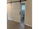 Close up of modern barn door and new white bathroom with toilet and window at 5445 Ansley Trl, North Charleston, SC 29418