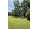 Large green grass yard with multiple trees and utility sheds in the distance at 6287 Sniders Hwy, Walterboro, SC 29488