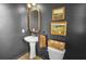 Stylish powder room featuring a pedestal sink, elegant mirror, and decorative wall art, offers a convenient space at 716 Mcroy St, Moncks Corner, SC 29461
