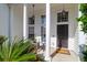 Inviting front porch with stately columns, a cozy seating area, and views of lush greenery at 7302 Sanderling Ct, Hanahan, SC 29410