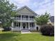 Charming two-story home features a double porch, green lawn, and mature trees enhancing curb appeal at 911 Hunt Club, Charleston, SC 29414