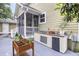 An outdoor kitchen with a concrete countertop, stainless steel drawers, and a mini fridge sits next to a screened porch at 911 Hunt Club, Charleston, SC 29414