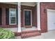 Close-up of a brick home's inviting front entrance featuring a black door, white columns, and a welcome mat at 116 Venezia Ct, Ladson, SC 29456