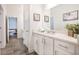 Bright bathroom showcasing white cabinetry, a large mirror, and stylish gray wood-look tile flooring at 1495 Keshi Pearl Dr, Mount Pleasant, SC 29466