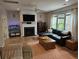 Cozy living room with a fireplace, large windows, hardwood flooring, and a comfortable brown leather sectional sofa at 1495 Keshi Pearl Dr, Mount Pleasant, SC 29466