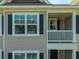 The home's tan siding exterior has black shutters and a small balcony in this shot at 1876 Towne St, Johns Island, SC 29455
