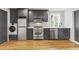 Modern kitchen featuring stainless steel appliances, sleek gray cabinets, a washer/dryer combo, and hardwood floors at 19 Smith St # D, Charleston, SC 29401