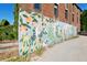 Colorful mural of plants and fruit decorating the side of a brick building near parking at 2 Francis St # I, Charleston, SC 29403