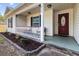 Inviting front porch with seating area, decorative plants and a red entry door at 210 Basswood Ave, Summerville, SC 29483