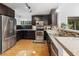 Kitchen with stainless appliances, dark wood cabinets, granite counters, mosaic tile backsplash, and wood floors at 210 Basswood Ave, Summerville, SC 29483
