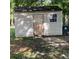 Exterior view of a weathered outbuilding with a small window, set amidst lush greenery and brick pathway at 214 Winter St, Moncks Corner, SC 29461